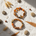 Earthy beaded bracelet set flat lay on white linen with dried botanicals